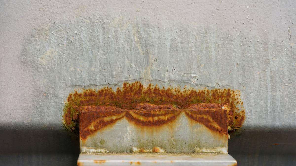 Electrolytic diy rust remover solution setup with battery charger and rusted tools in plastic tub
