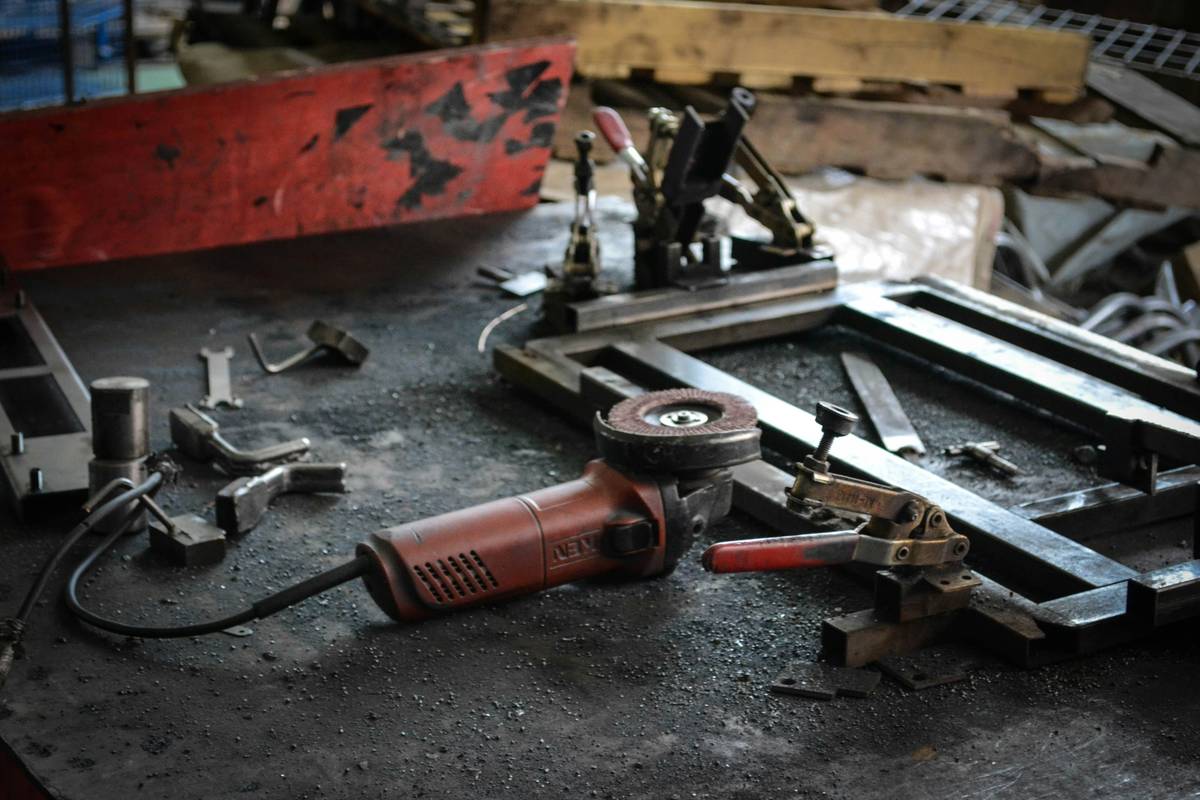 Setup for electrolytic rust removal method showing bucket, battery charger, and rusty tool submerged
